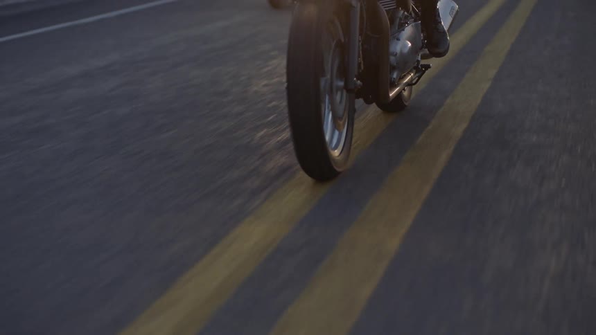 A person drives a motorcycle down a street