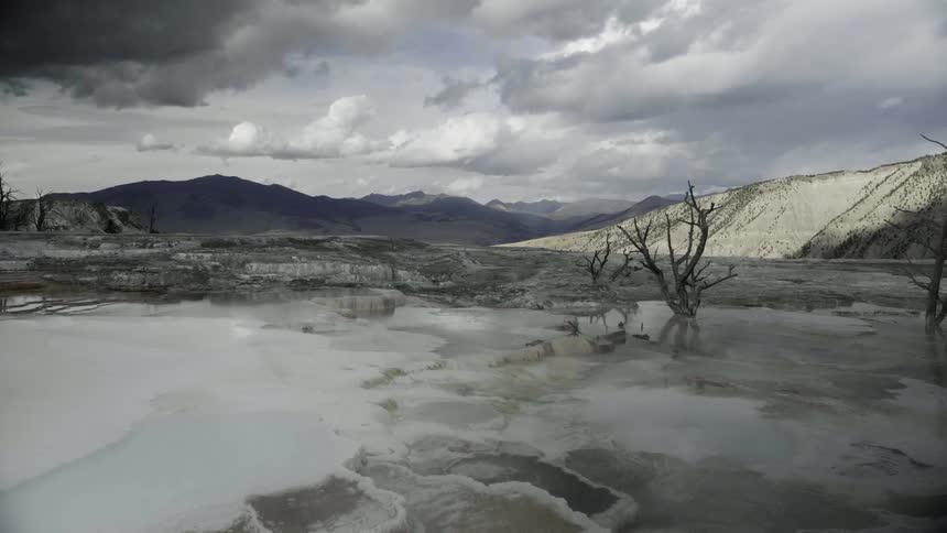 Steam rises from hot spring in barren desert landscape