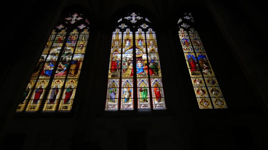 Stained glass windows lit up in a darkened church