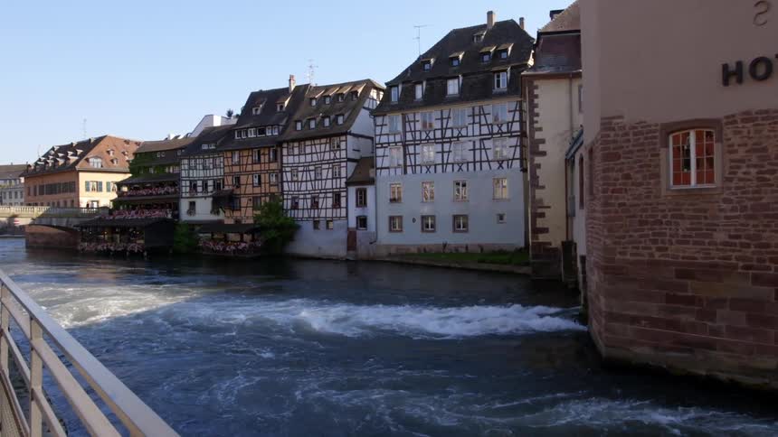 Water pours out of a drain attached to a row of buildings