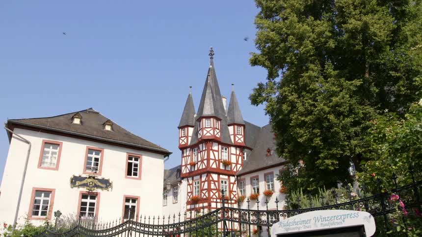 An old house with large spires sits behind a metal fence