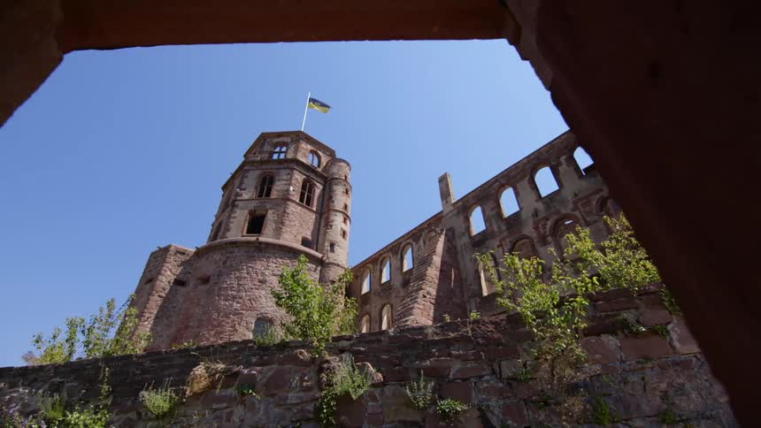 A flag flies atop on old tower next to a stone wall