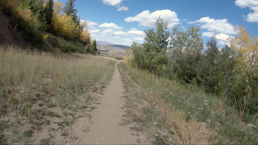 Person travels on a trail near a hill on a sunny day