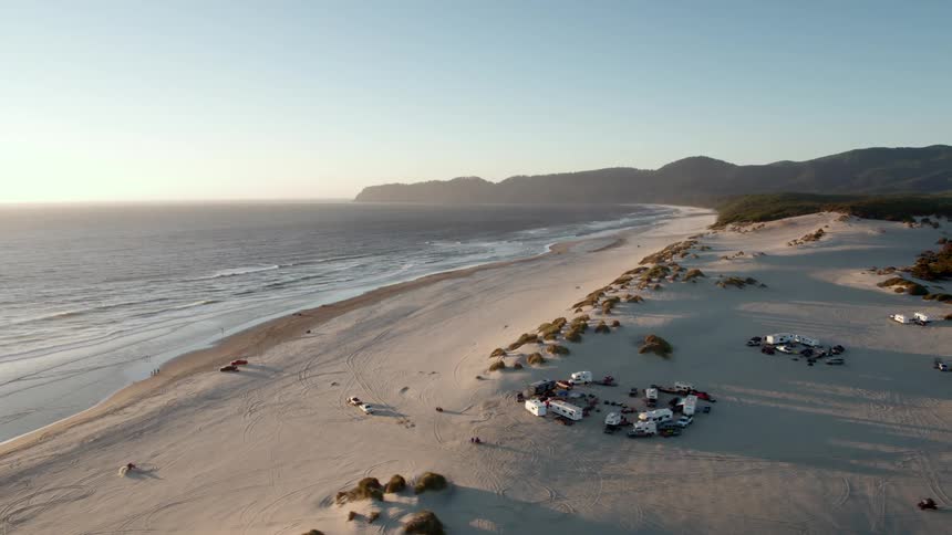 People cross beach on four wheel vehicles near camps
