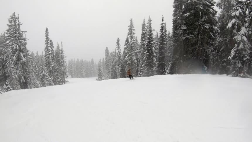 Person snowboarding down hill in heavy snow