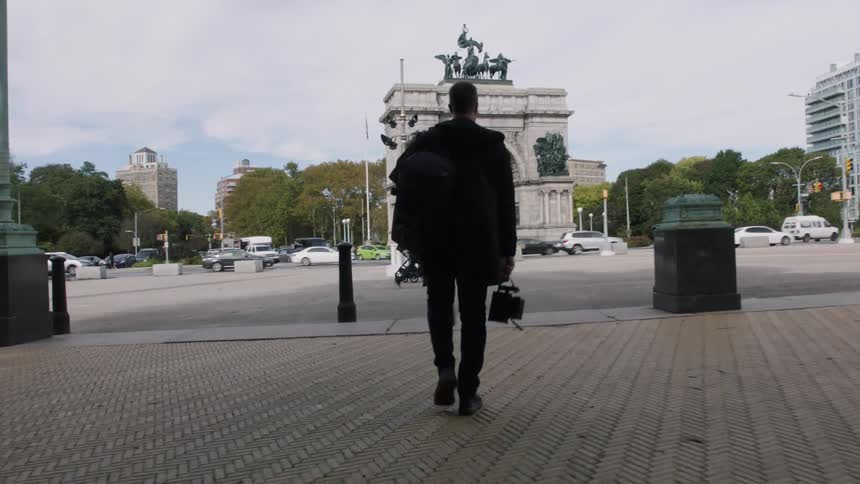 A man is walking outdoors in a downtown city