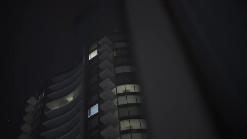 Low angle view of modern city buildings towering overhead at night.
