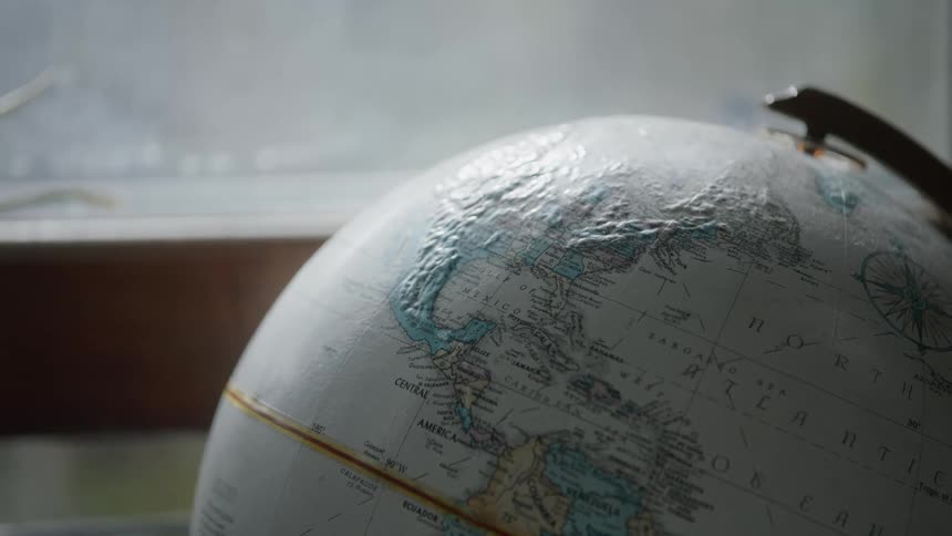 A globe on a stand sits by a window in a room