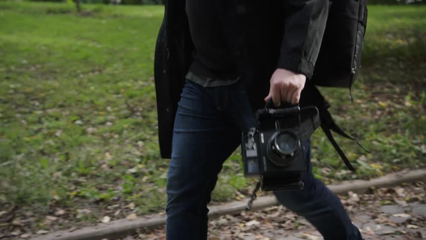 A photographer walks along with his camera