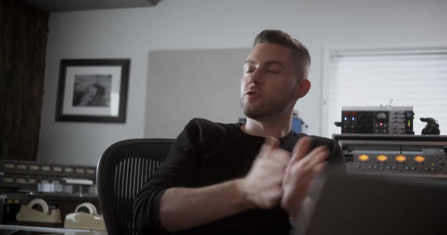 A man sitting in an office talks animatedly with his hands