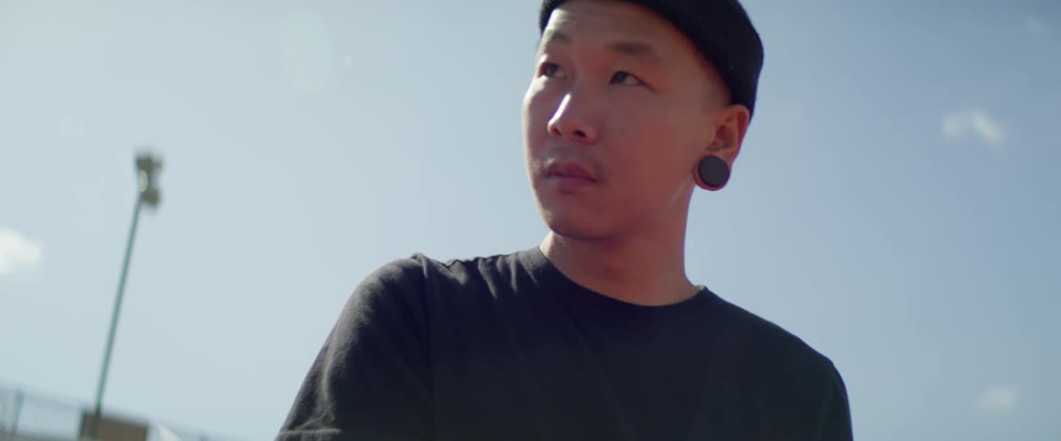 A male asian teenager stands outside and looks around