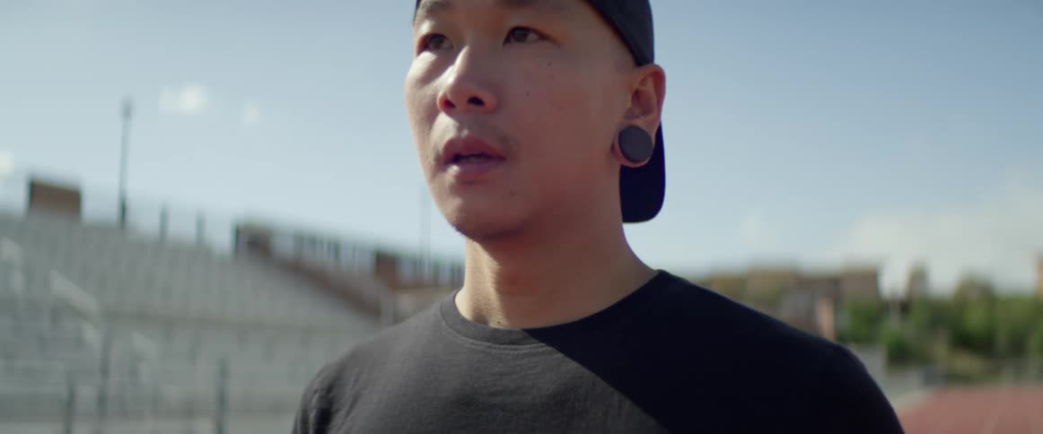 A man stands at an empty track blowing out a deep breath on a sunny day