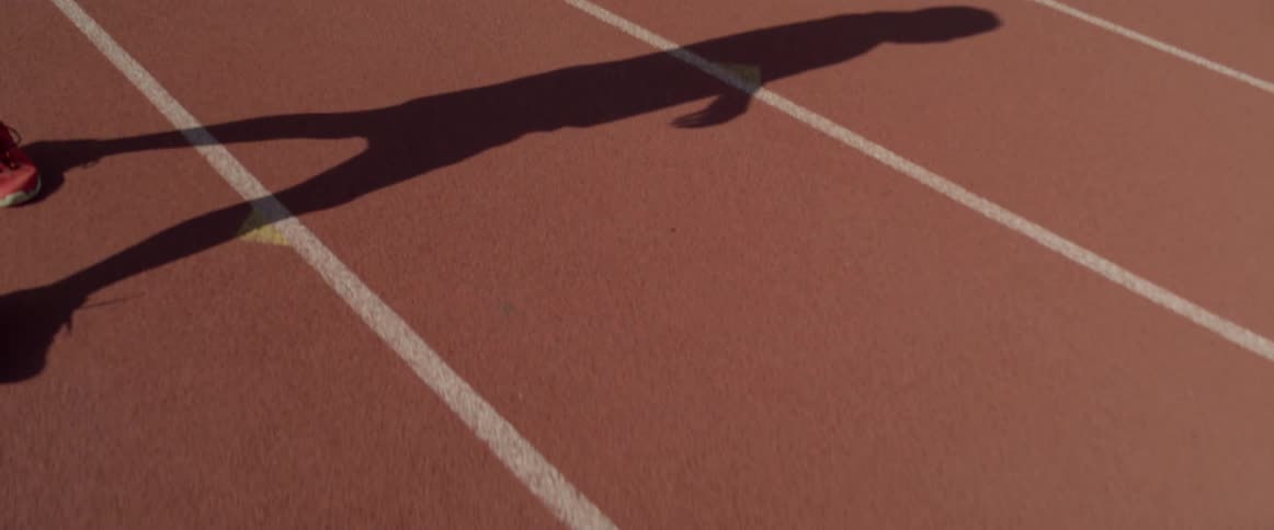 A mans shadow is shown as he walks along a track