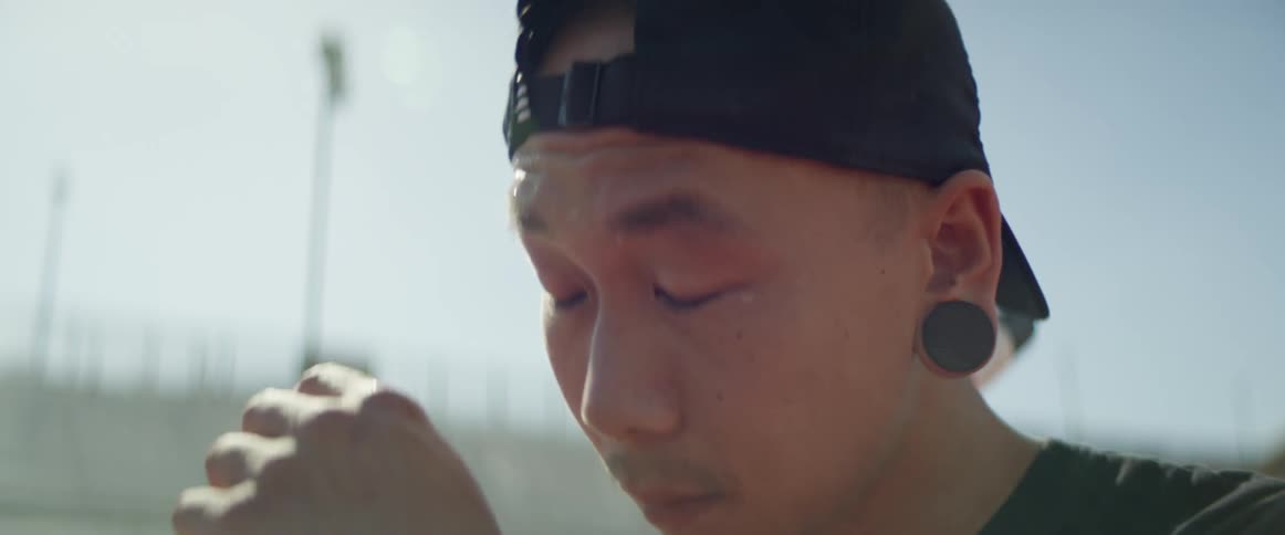 A man standing and wiping the sweat from his brow with the sky in the background