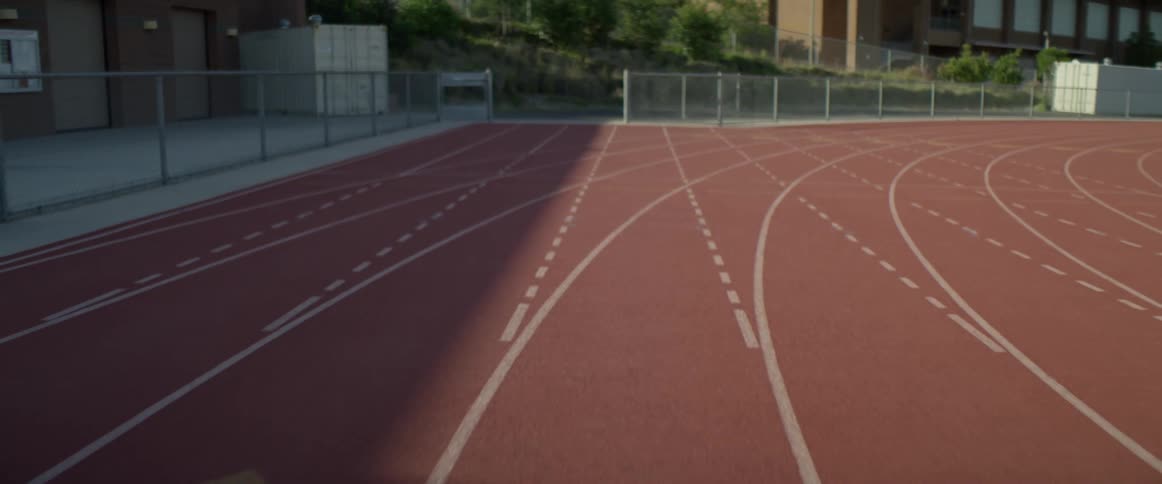An empty track and field outside of several buildings