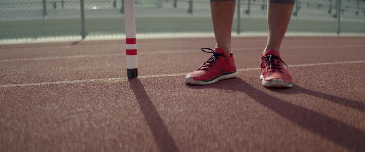 A persons feet with red sneakers on a running track