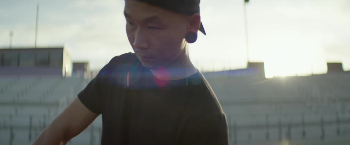 An asian man stands in a stadium holding a boom mike
