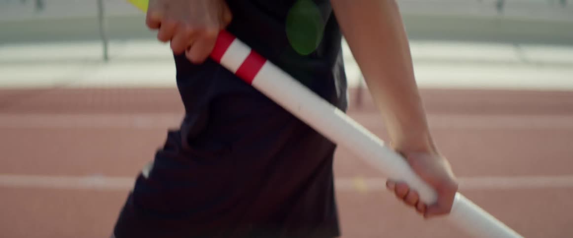 Man carries a vaulting pole as he runs down the track