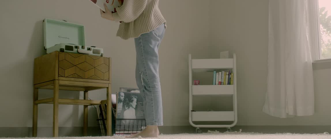 A woman organizes a room with records and a record player