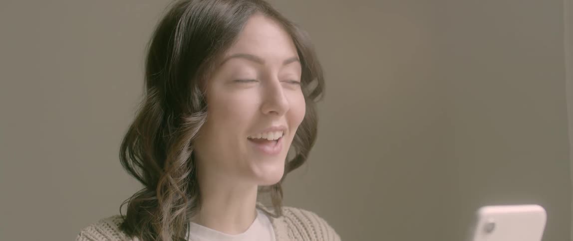 An asian woman laughs while talking on a smartphone