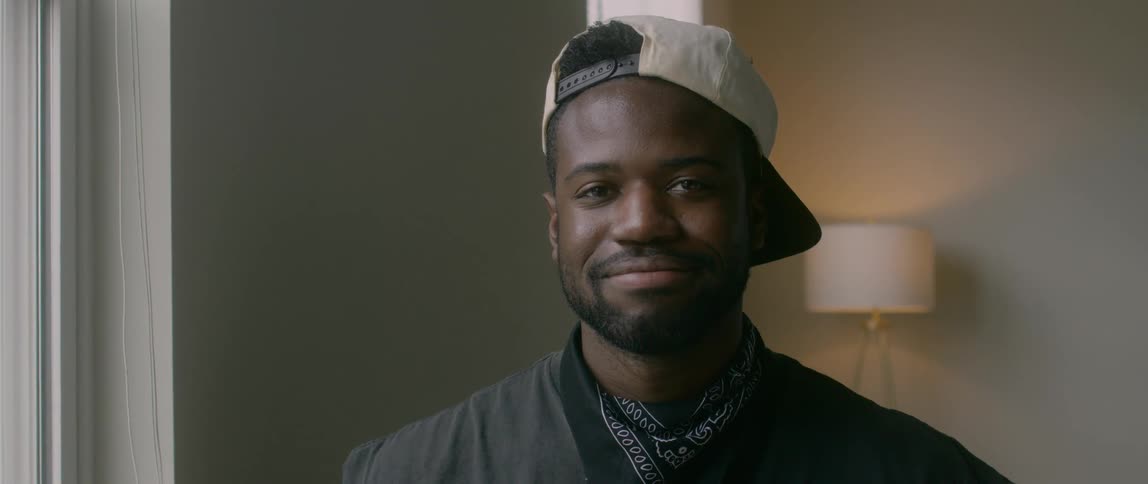 A man looking out a window and turns and starts to stare and smile