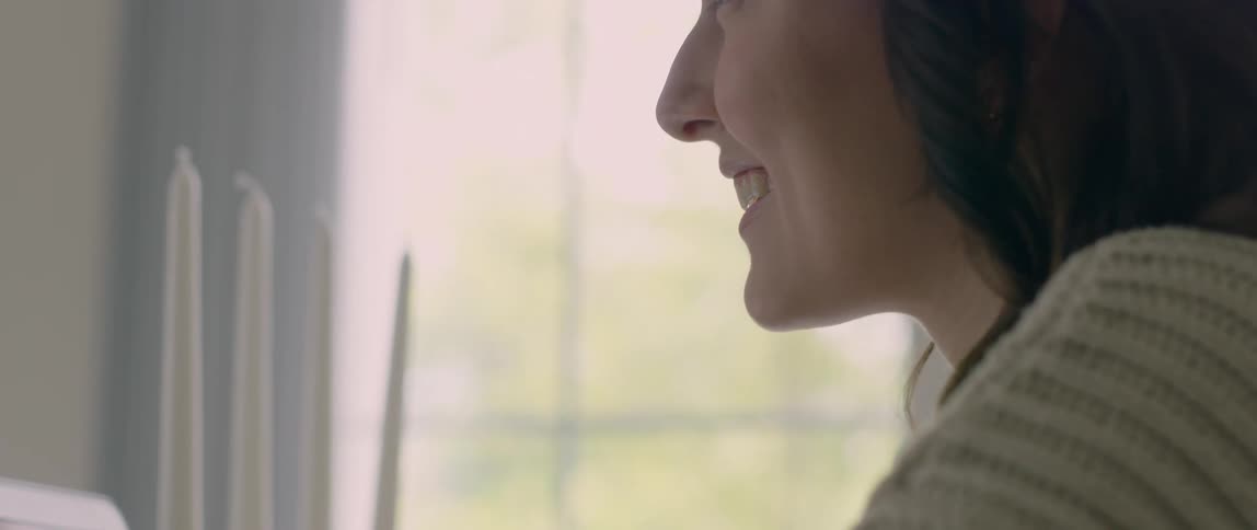 A woman is smiling and looking at a computer screen