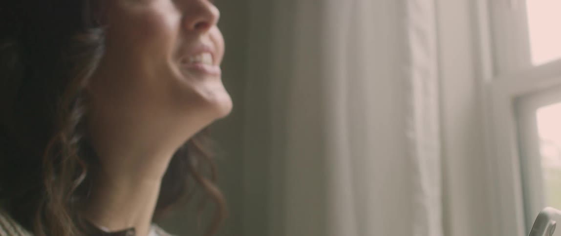 Happy woman having a conversation on cell phone near a window indoors