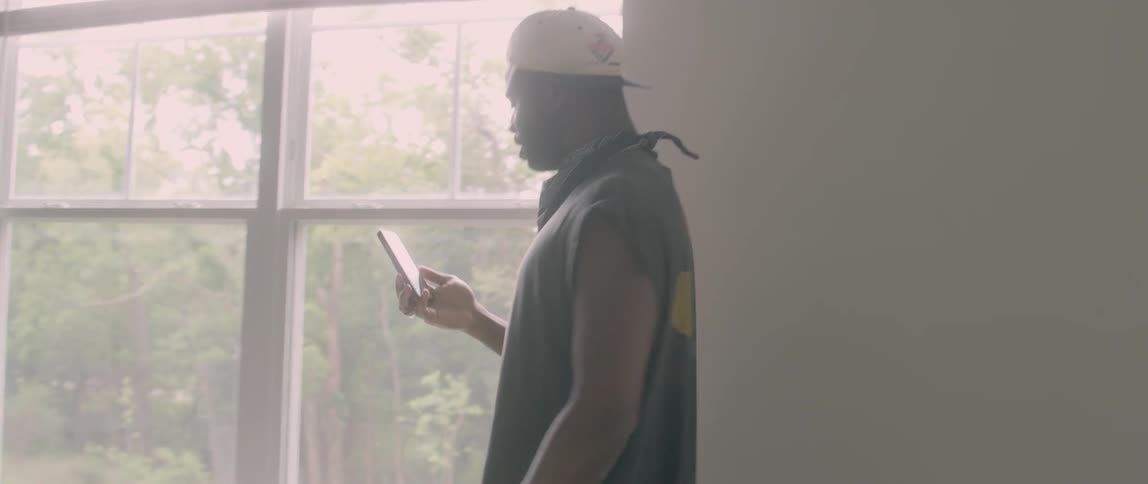 A man walks over to the window talking on his phone