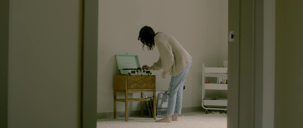A woman puts a record on an old record player