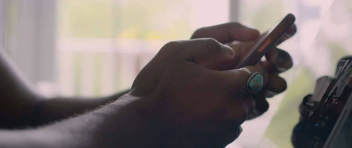 A person wearing a large ring scrolls on a smartphone