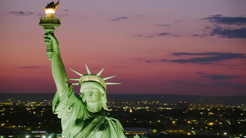 The statue of liberty with the city and the sky in the background