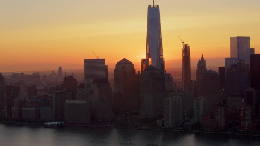 The sun sets over downtown of a city next to a river