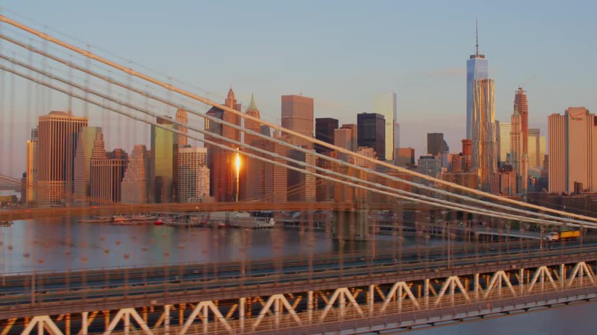 New york city skyline behind brooklyn bridge at sunset