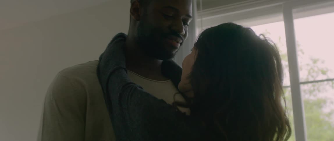 A black man and an asian woman dance in a home