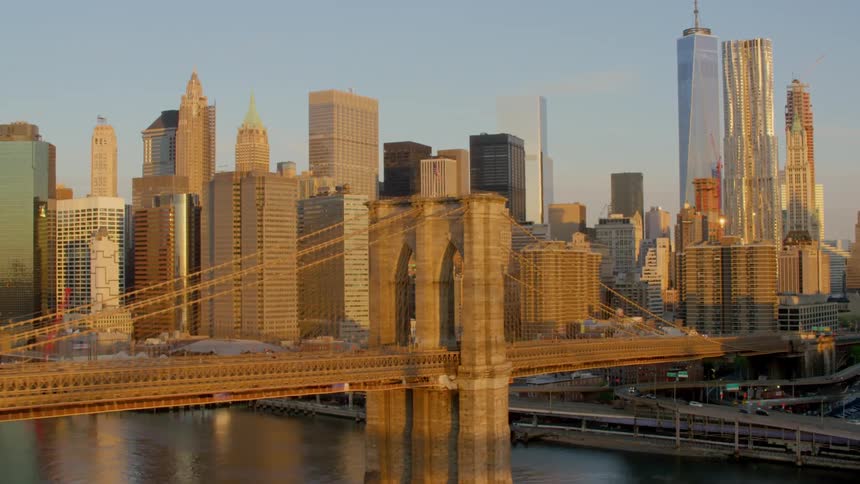 A suspension bridge crosses a river near the downtown area of a city