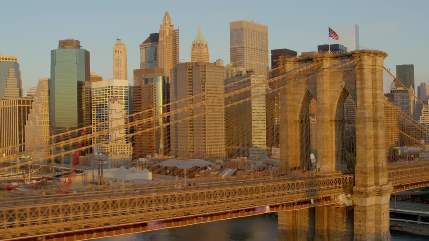 A suspension bridge stretches over a river into a city