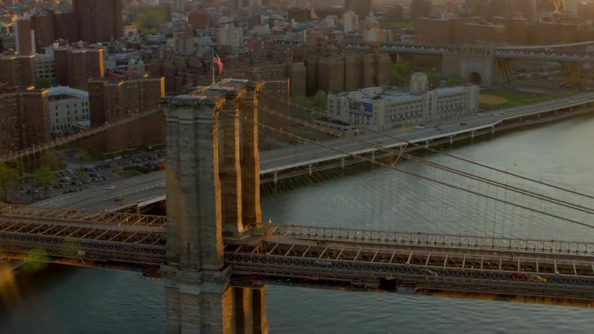 A bridge with an american flag on top with the city skyline in the background