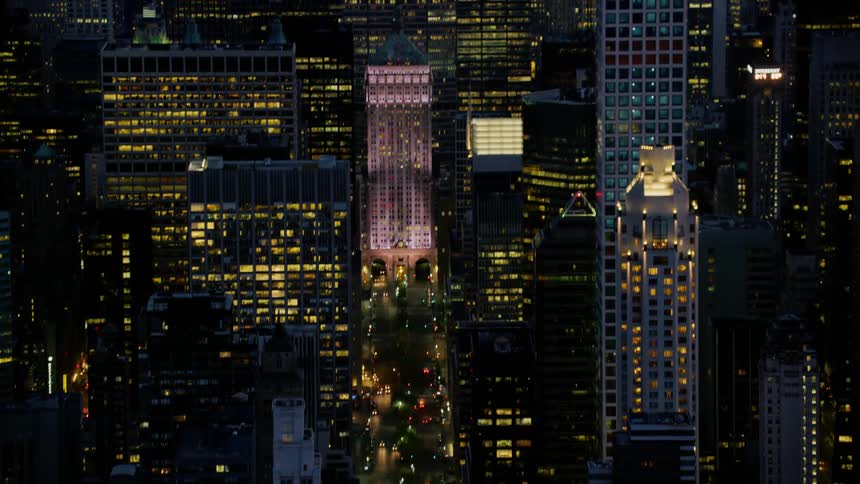 A large street runs straight through a large downtown urban area at night