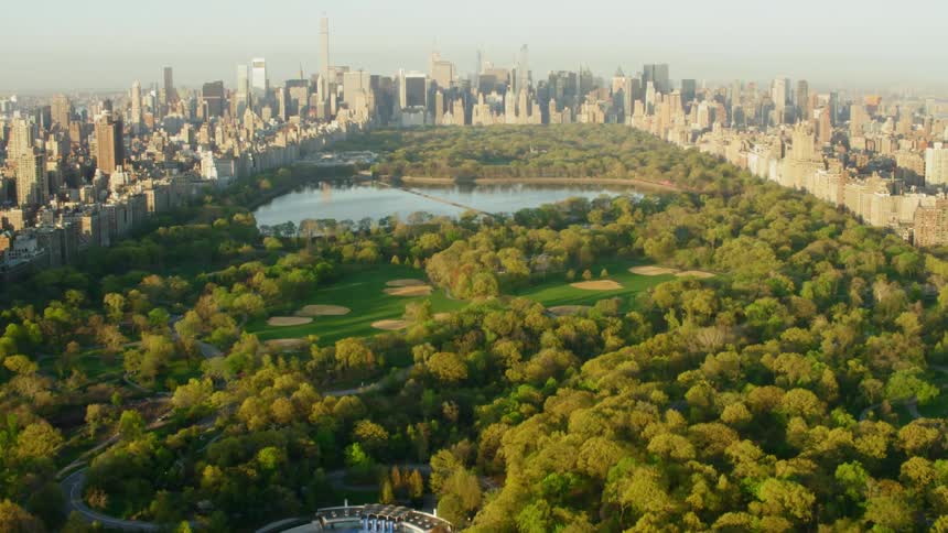 A large park with a golf course and lake sits in the middle of a large downtown area