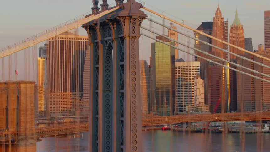 Sunlight hits and reflects off skyscrapers in a city skyline behind two bridges