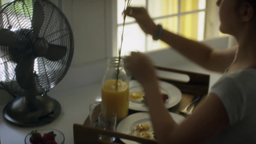 A girl placing carnations in a bottle of orange juice