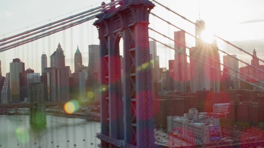 Manhattan bridge with manhattan skyline in background at sunset