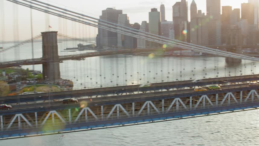 Traffic moves across a suspension bridge into a city