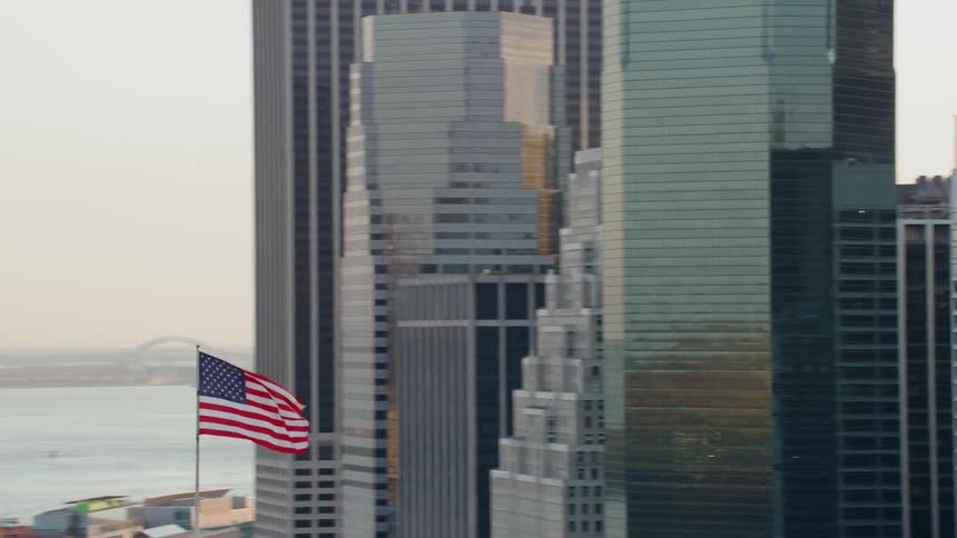 An american flag flies in a city near a river
