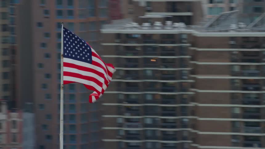 An american flag blows in the wind in the downtown area of a city