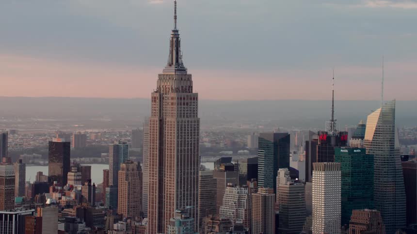 Sun turns horizon orange behind water and empire state building