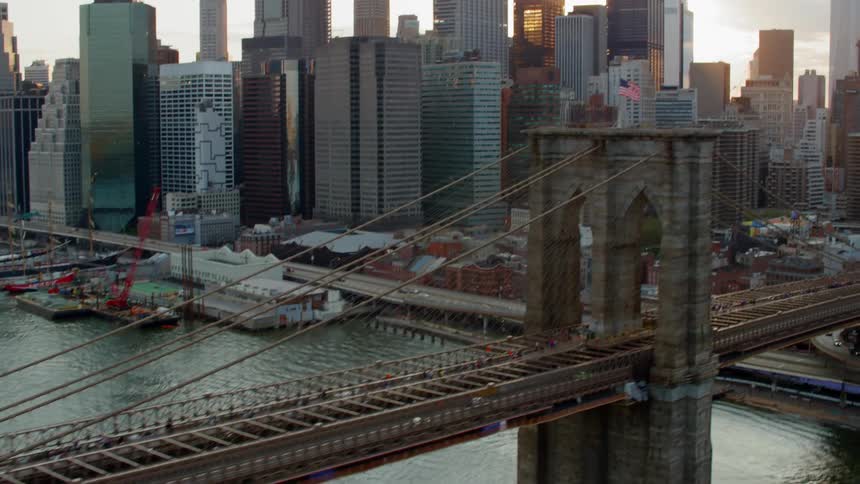 A bridge with vehicles and an american flag on top with the city skyline in the background