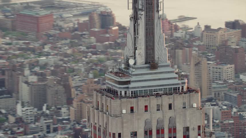 A crowd of people stand on an observation deck on top of a tall skyscraper