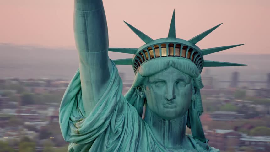Statue of liberty image against town of low rise buildings and mountains