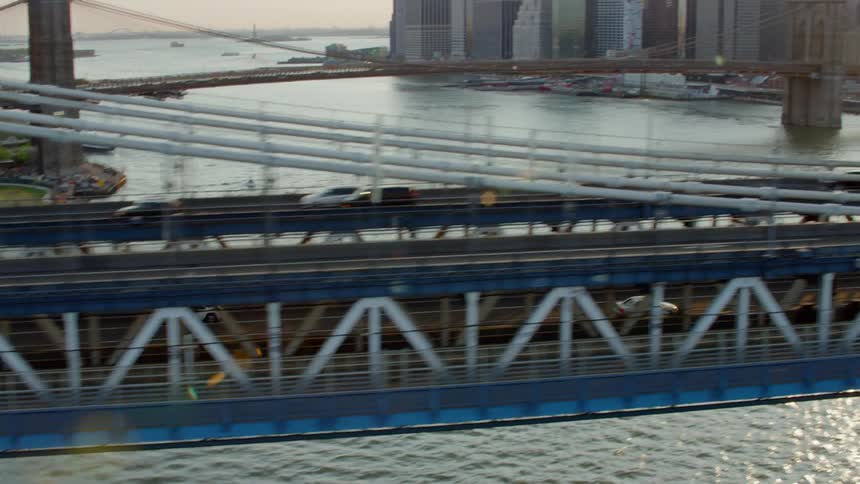 Cars drive across a suspension bridge linked to a city